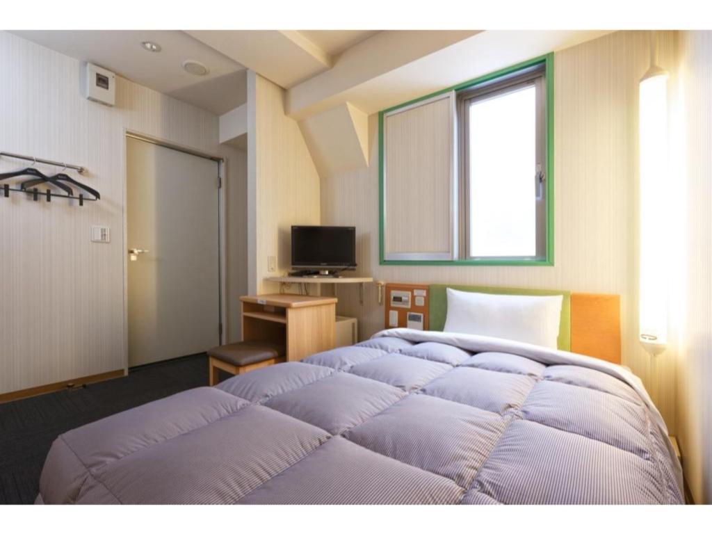 1 Schlafzimmer mit 2 Betten, einem Schreibtisch und einem Fenster in der Unterkunft R&B Hotel Kobe Motomachi - Vacation STAY 15387v in Kōbe