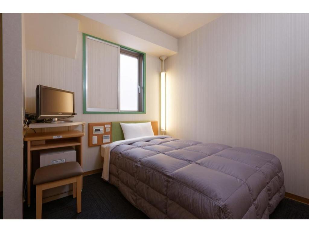 a bedroom with a bed and a desk with a television at R&B Hotel Kobe Motomachi - Vacation STAY 15385v in Kobe