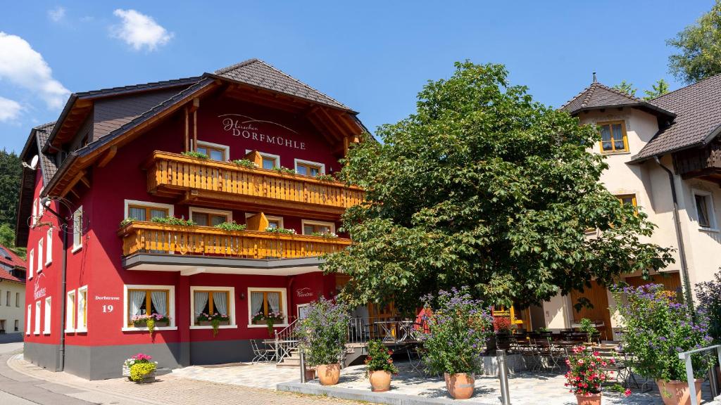 un edificio rojo con un árbol delante de él en Hirschen-Dorfmühle en Biederbach Baden-Württemberg