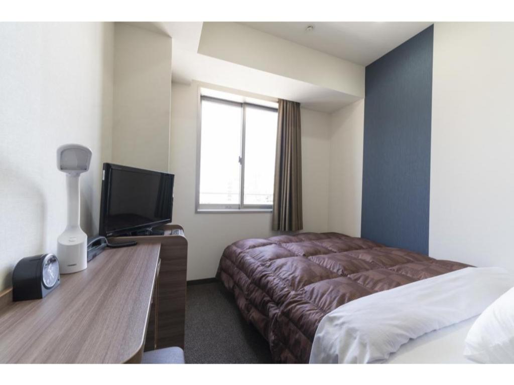 a hotel room with a bed and a desk with a television at R&B Hotel Hakata Ekimae 2 - Vacation STAY 16429v in Fukuoka