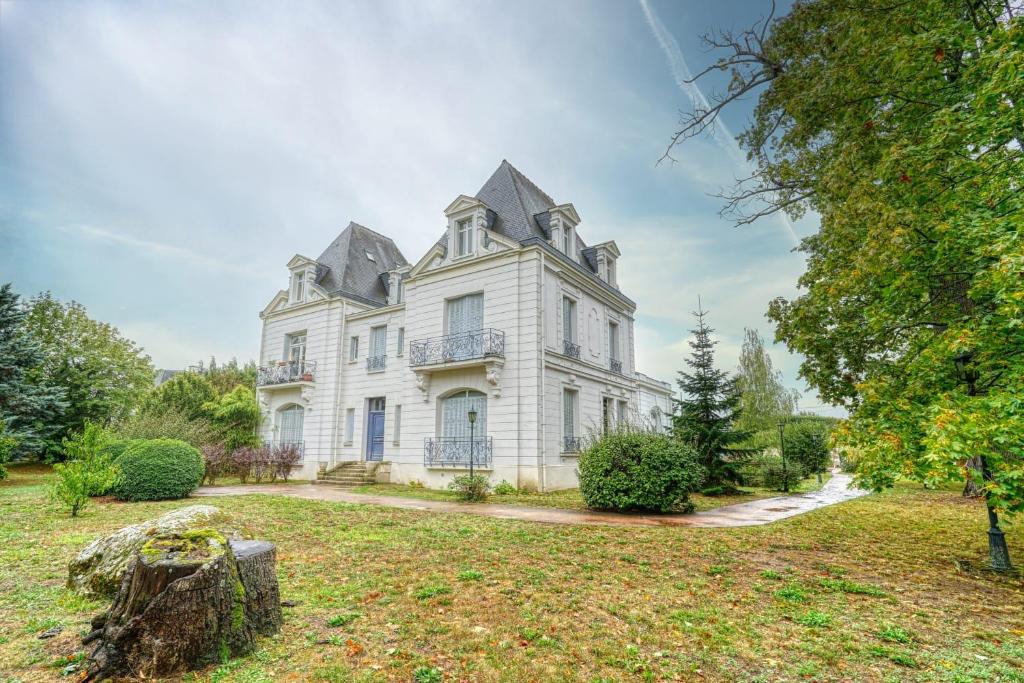 a large white house with a roof at La Reine Blanche in Dammarie-lès-Lys