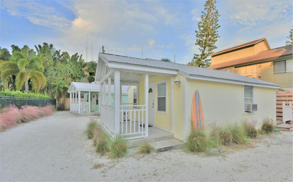 a small house on the beach with a surfboard at Charming Beach Cottage Steps to Siesta Beach and Village Shops and Restaurants in Sarasota