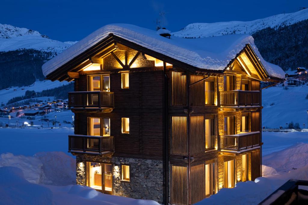 Un bâtiment avec des lumières allumées dans la neige dans l'établissement Moon Eco B&B, à Livigno