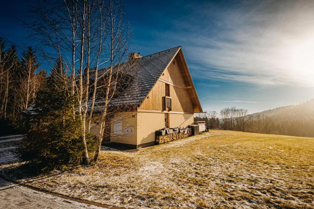 a barn in a field with the sun in the sky at Horský apartmán U Lesa Říčky in Říčky