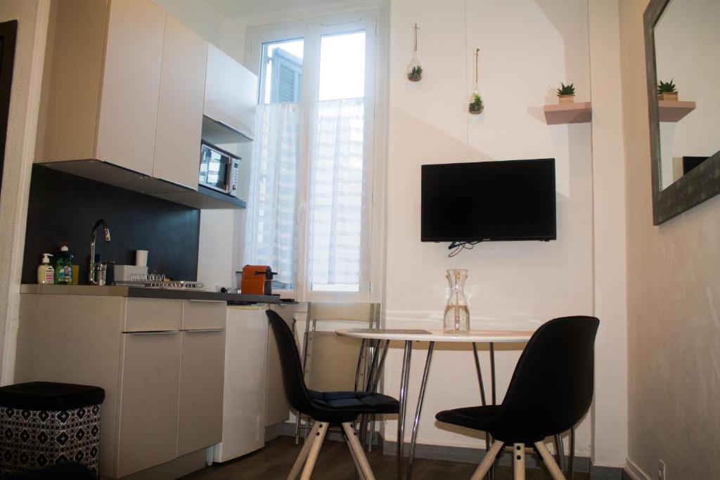 eine Küche mit einem Tisch und Stühlen sowie einen TV an der Wand in der Unterkunft Appartement palais plages in Cannes