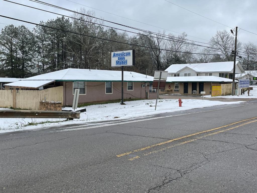 a building on the side of a street with a sign at American Inn Motel in Many