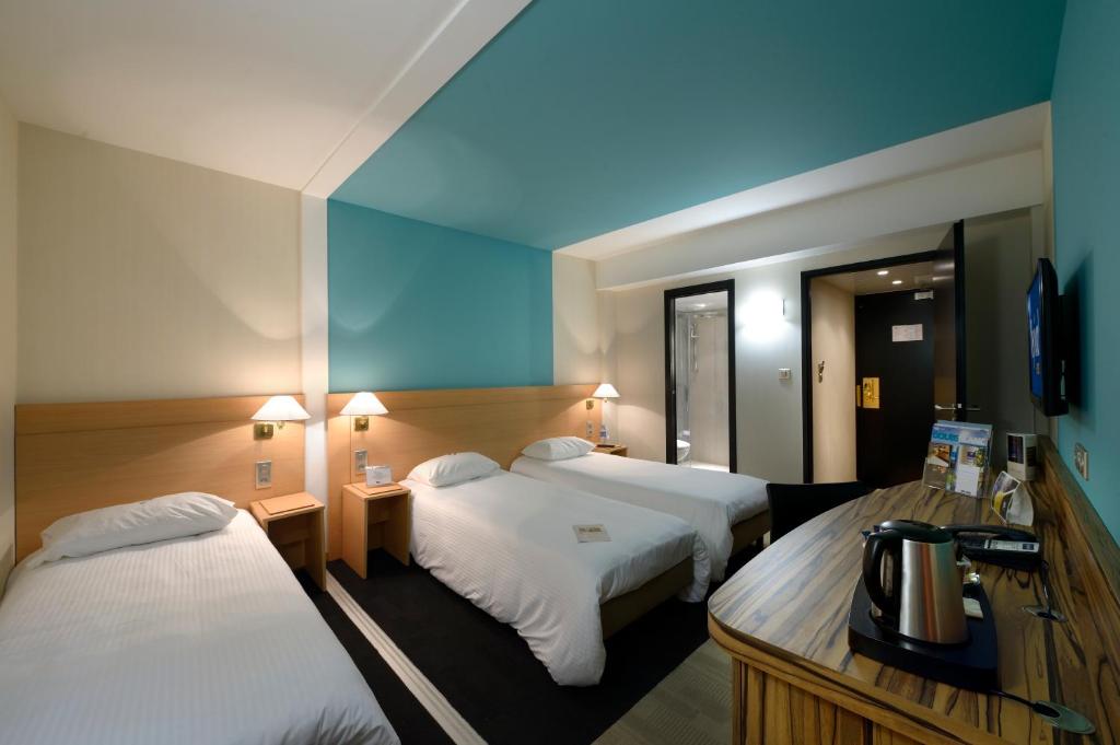 モンベリアルにあるKyriad Montbeliard Sochauxのベッド2台と鏡が備わるホテルルームです。