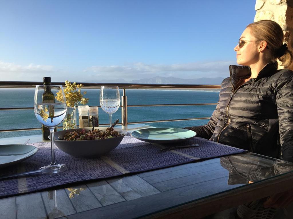 una mujer sentada en una mesa con copas de vino en Kleinzee Oceanfront Guesthouse, en Gansbaai