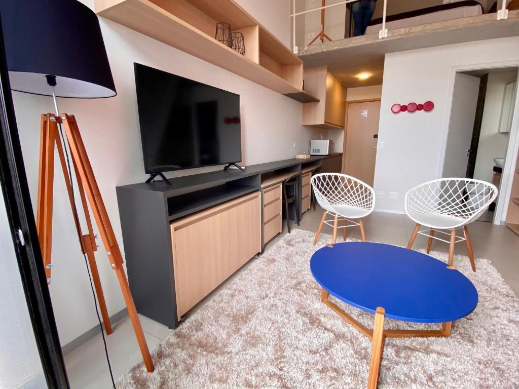 uma sala de estar com uma televisão e duas cadeiras e uma mesa em 45LOFT EM DE MARILIA TODO DECORADO/ARCOND em Marília