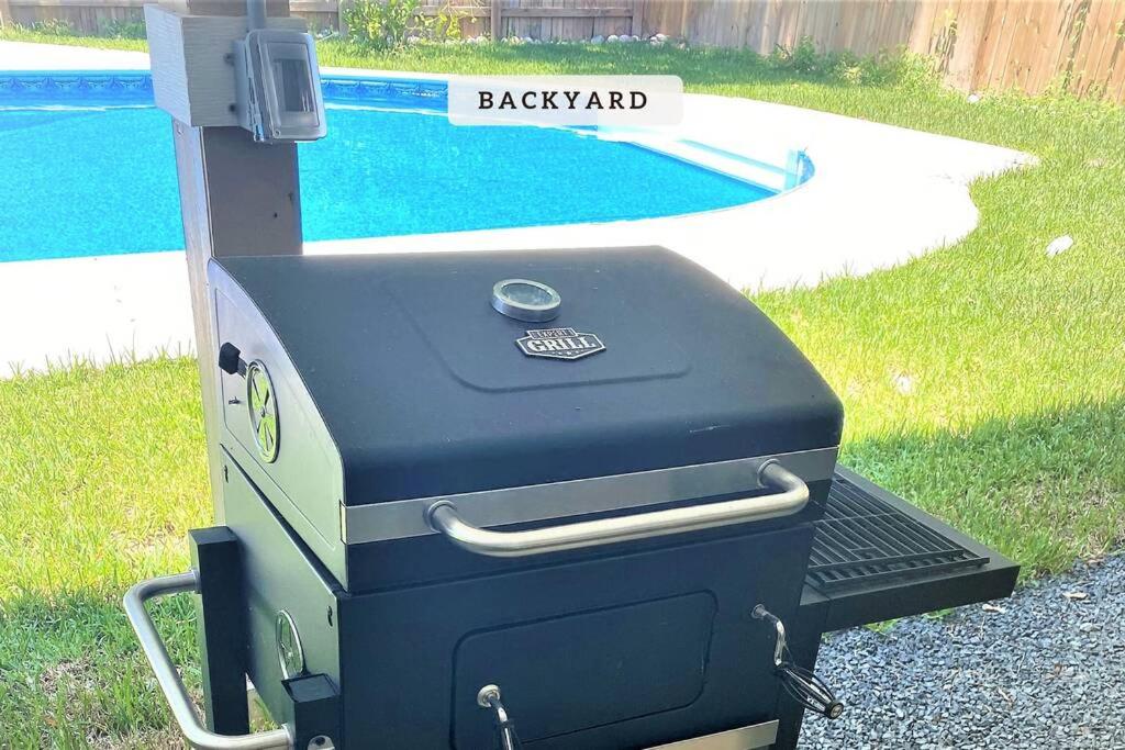 a barbecue grill sitting next to a swimming pool at Vacation Pool House in the Serene Wilderness - Robert E Lee in Conroe