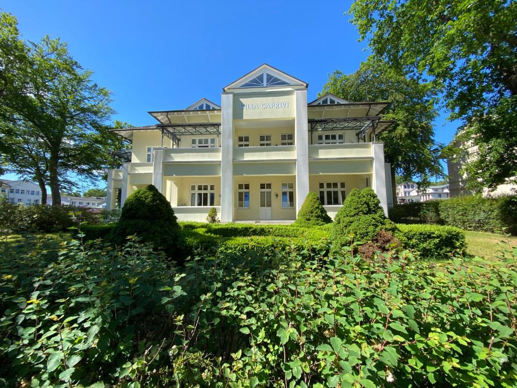 a large white building on a hill with bushes at Villa Caprivi 1 in Heringsdorf