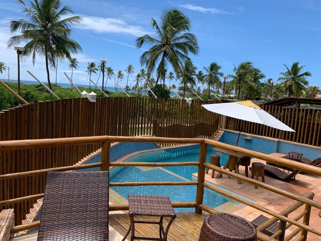 a deck with a pool and chairs and an umbrella at Villaggio Orizzonte in Salvador