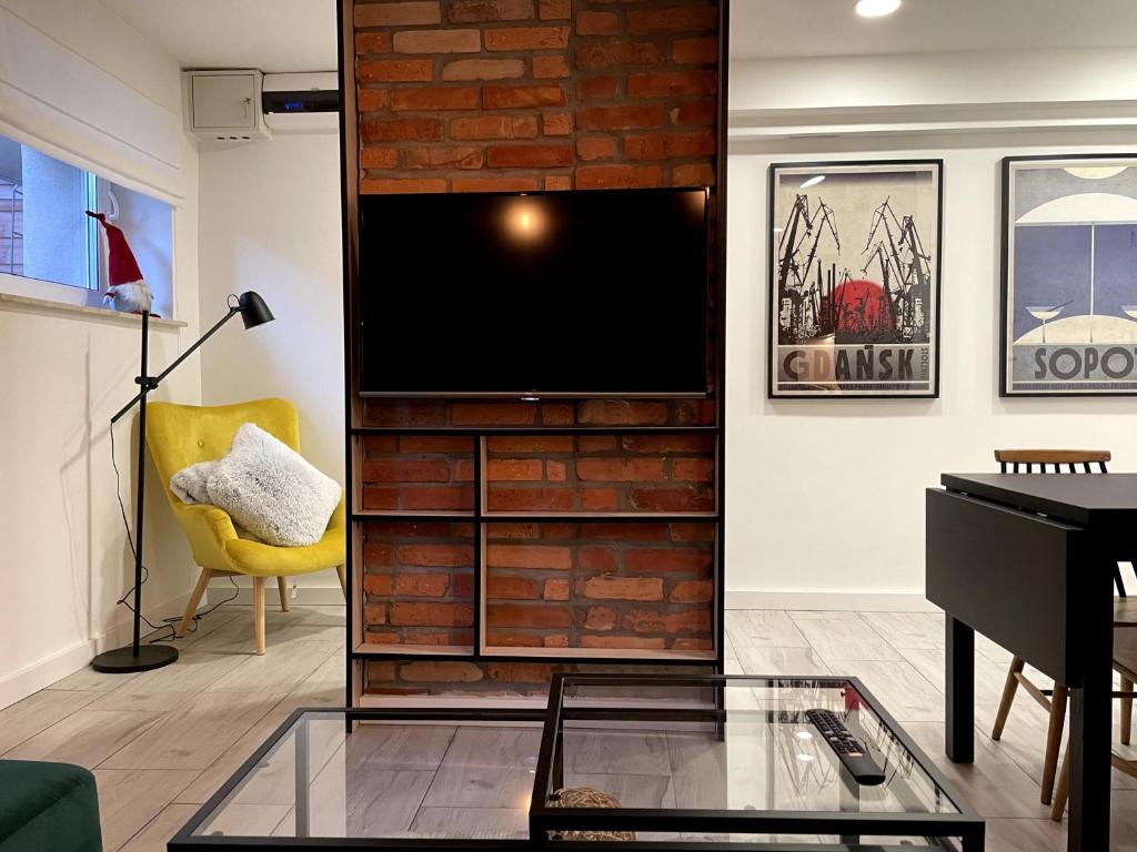 a living room with a television on a brick wall at Apartament2 Tri-City Oliwa Ogród, prywatne wejście in Gdańsk