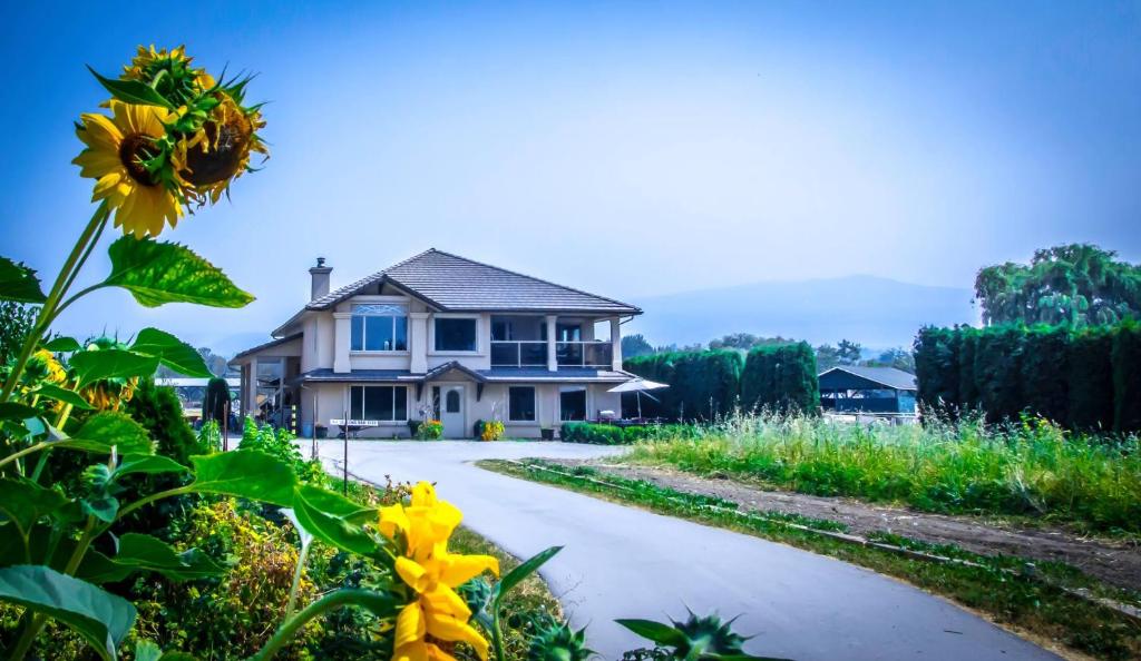 a house with yellow flowers in front of a driveway at All Seasons Bed & Breakfast in Kelowna