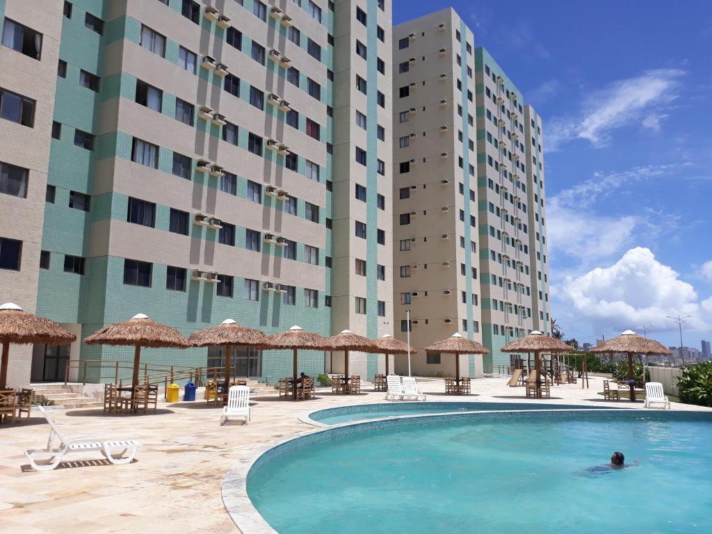 a swimming pool in front of a hotel with tall buildings at Apartamento BEIRA-MAR com 2 quartos in Maceió