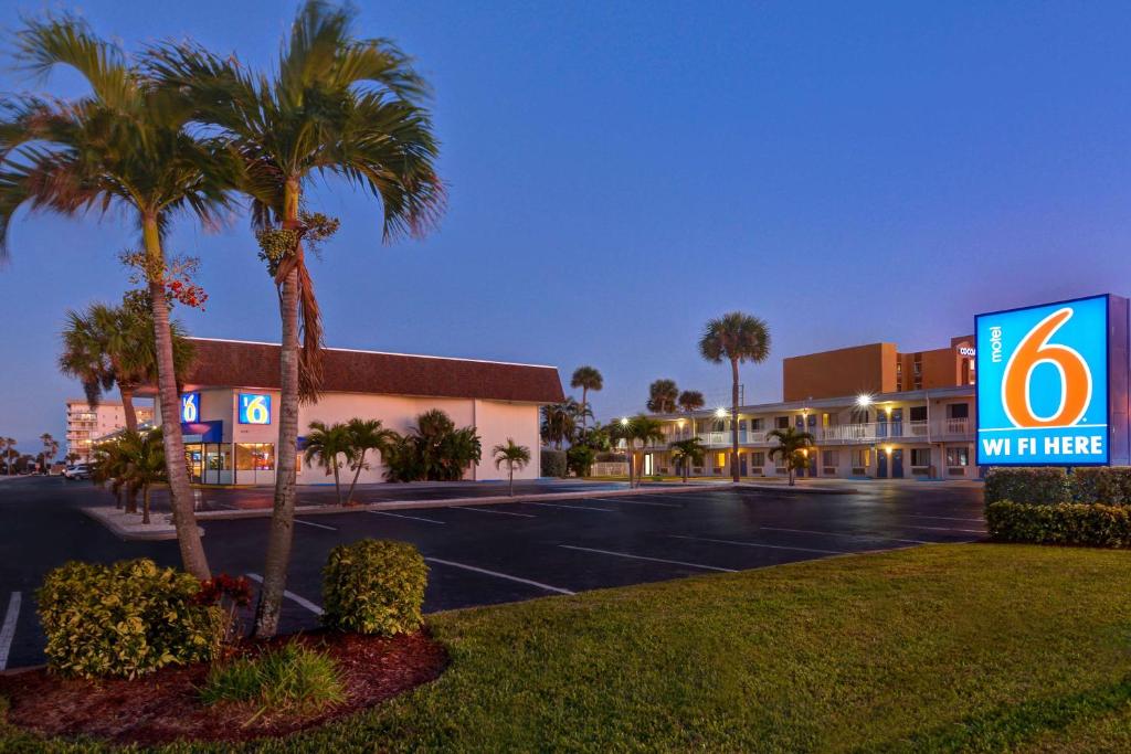 um edifício com uma placa em frente a um parque de estacionamento em Motel 6-Cocoa Beach, FL em Cocoa Beach
