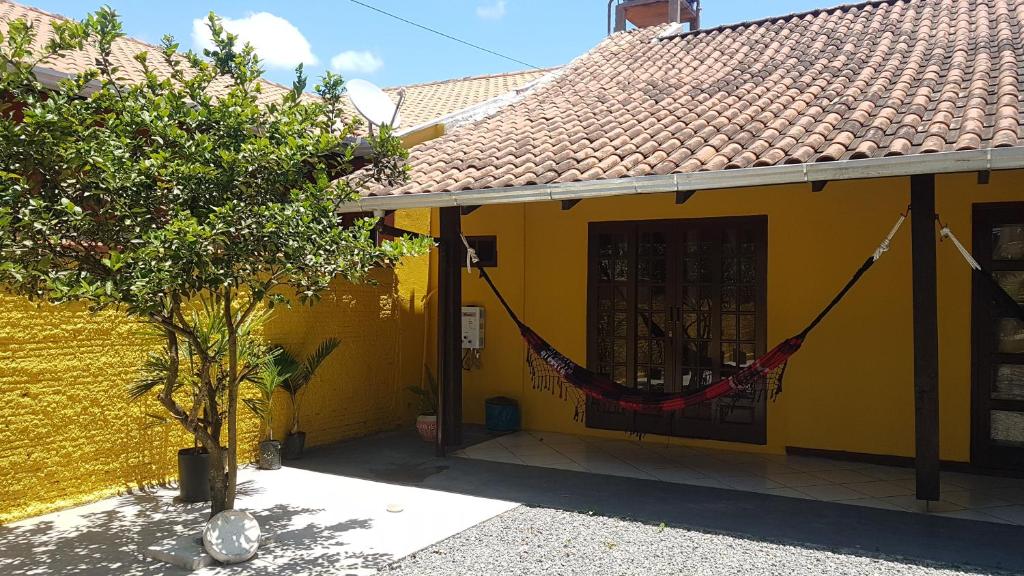 żółty dom z hamakiem wiszącym na nim w obiekcie Pousada Bali Surf House -Suíte 1 w mieście Balneário Piçarras