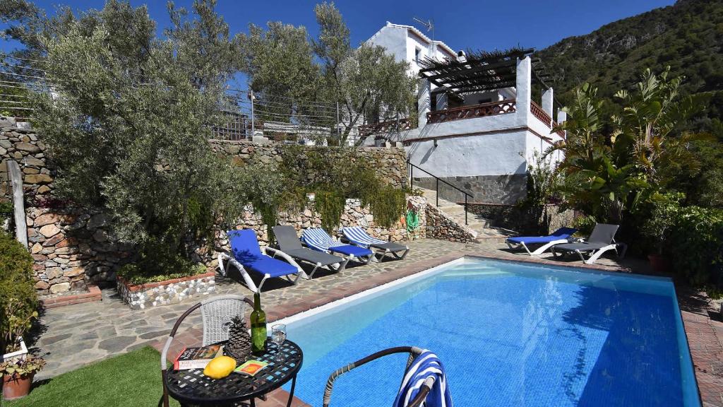 a swimming pool with blue chairs and a house at Frigiliana 015 in Frigiliana
