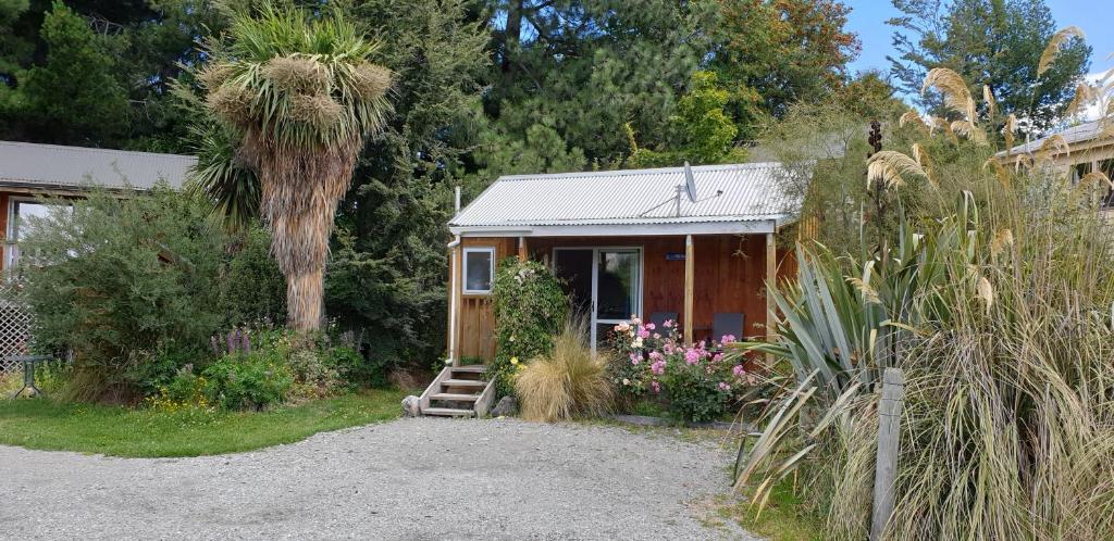 une petite maison avec un palmier en face dans l'établissement Lake Tekapo Cottages, à Lac Tekapo