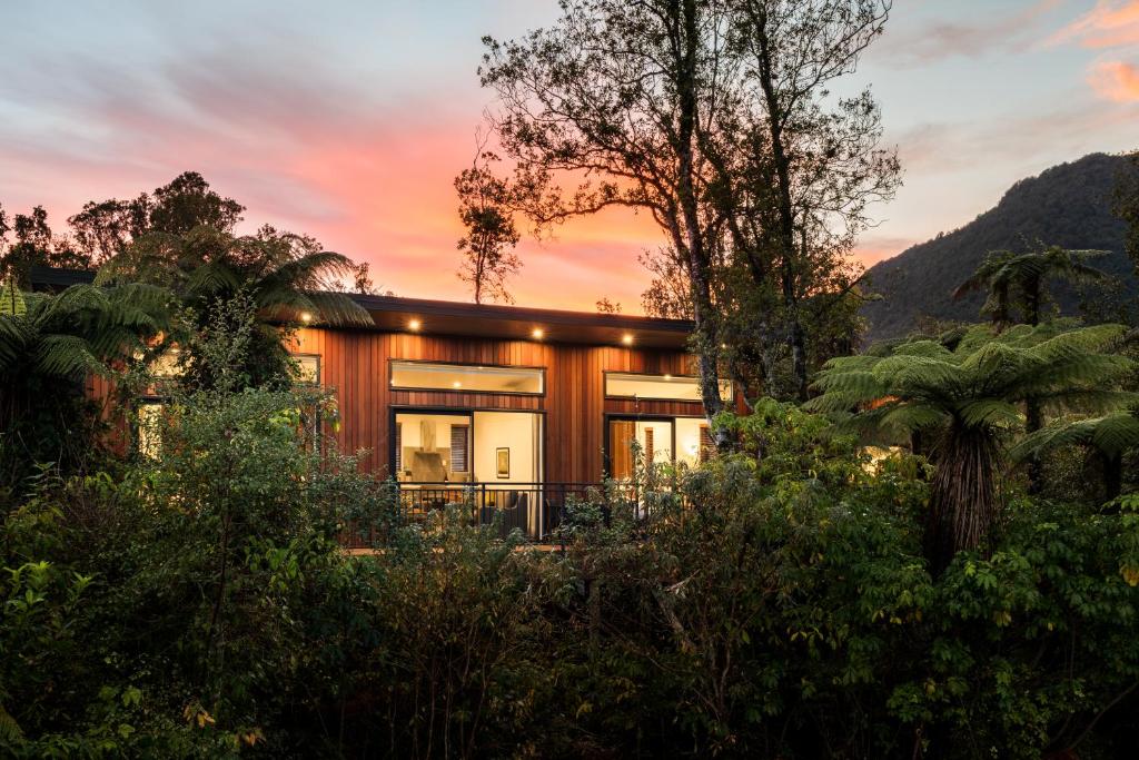 una casa en medio de un bosque al atardecer en Rainforest Deluxe en Franz Josef