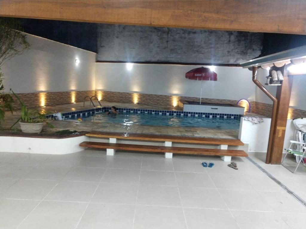 a large swimming pool with a bench in a room at Casa Ampla e confortável in São Sebastião
