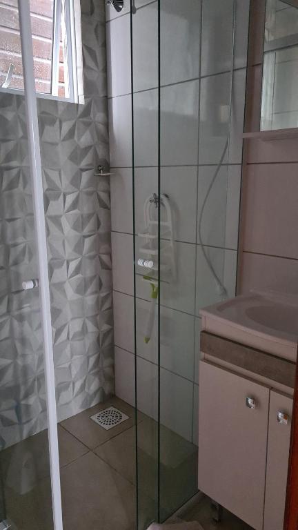 una ducha con una puerta de cristal junto a un lavabo en Recanto Aurora, en Massiambu Pequeno