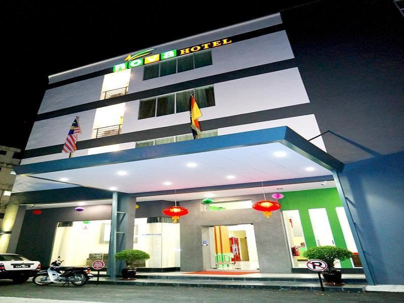 a building with a motorcycle parked in front of it at Nova Kuching Hotel in Kuching