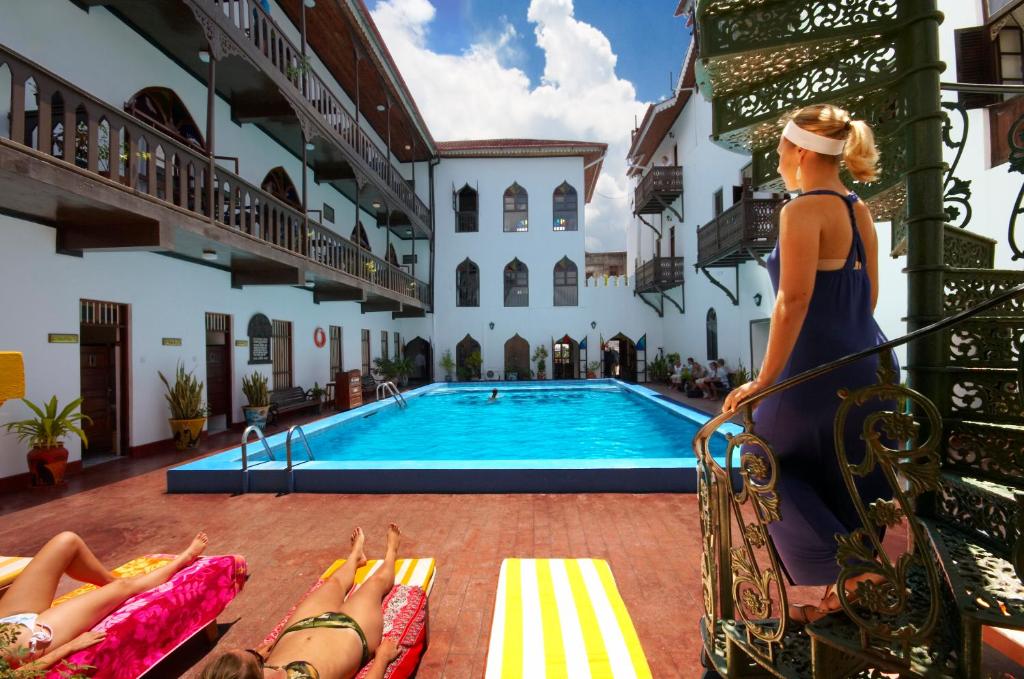 a group of people laying around a swimming pool at Tembo House Hotel in Zanzibar City