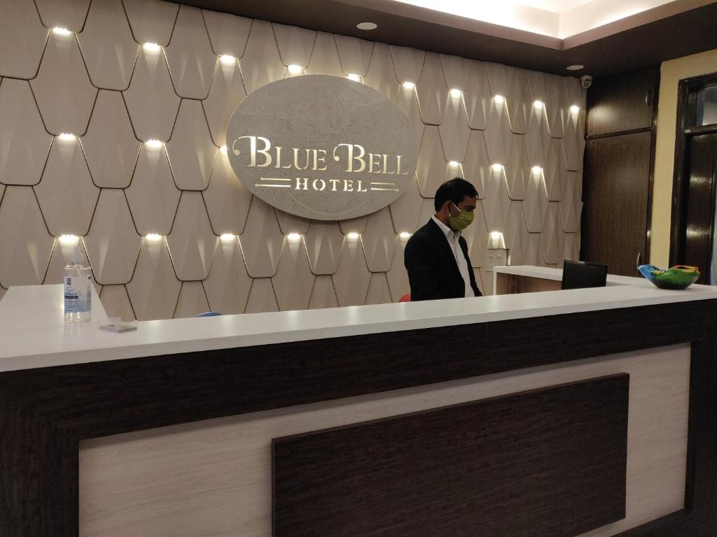 a man standing behind a counter in a blue bell hotel at Blue Bell Hotel - Greater Noida in Greater Noida