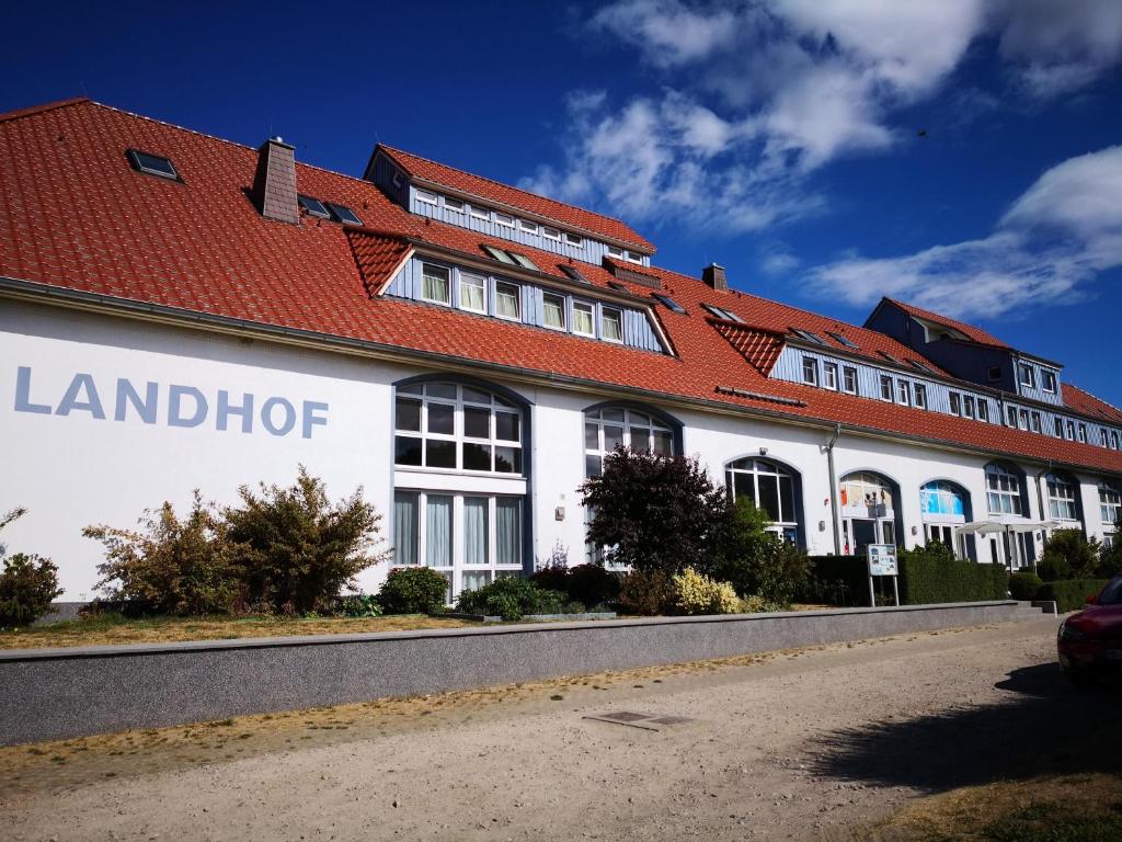 um grande edifício branco com um telhado vermelho em Der Landhof Wolgast em Stolpe auf Usedom