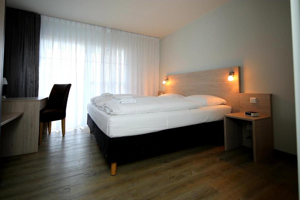 a bedroom with a bed and a desk and a chair at Der Landhof Wolgast in Stolpe auf Usedom