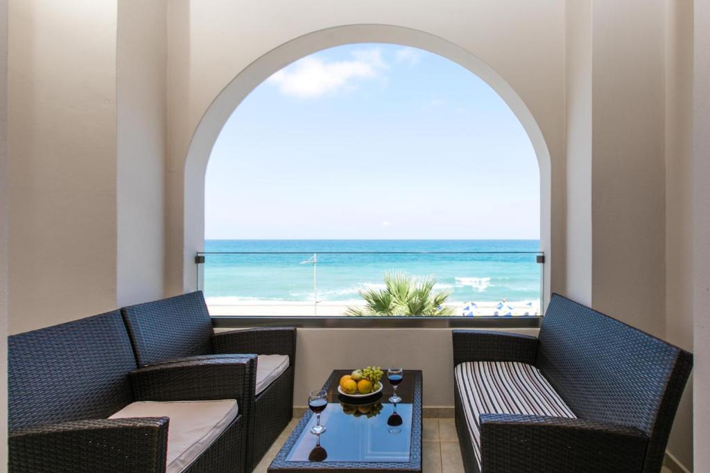 una camera con due sedie e un tavolo con vista sulla spiaggia di Marilyn Apartments a Rethymno