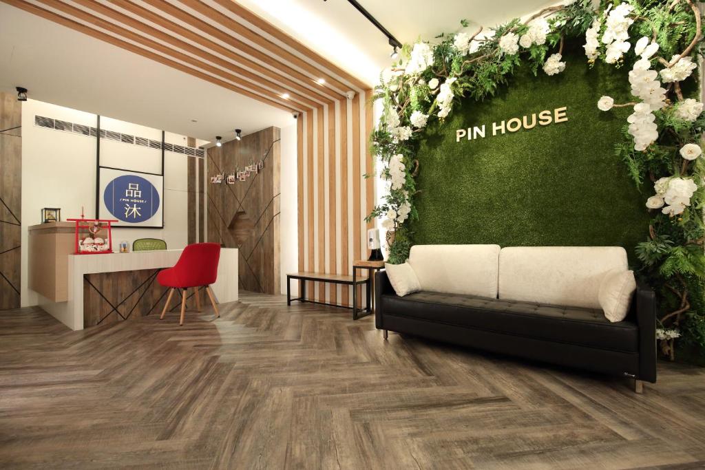 a living room with a couch and a green wall with flowers at Pin House in Hualien City
