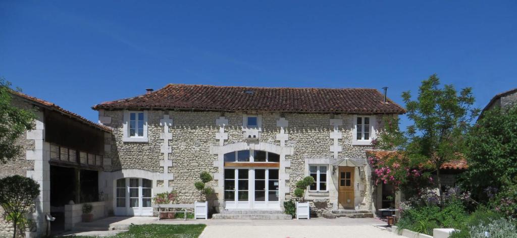 una gran casa de piedra con techo rojo en La Grange de Lucie -chambres d'hôtes en Périgord-Dordogne, en Nanteuil-de-Bourzac