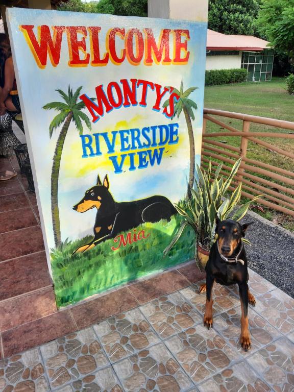 een hond staat voor een welkom bij navarre bord bij Monty's Riverside View Resort in San Antonio