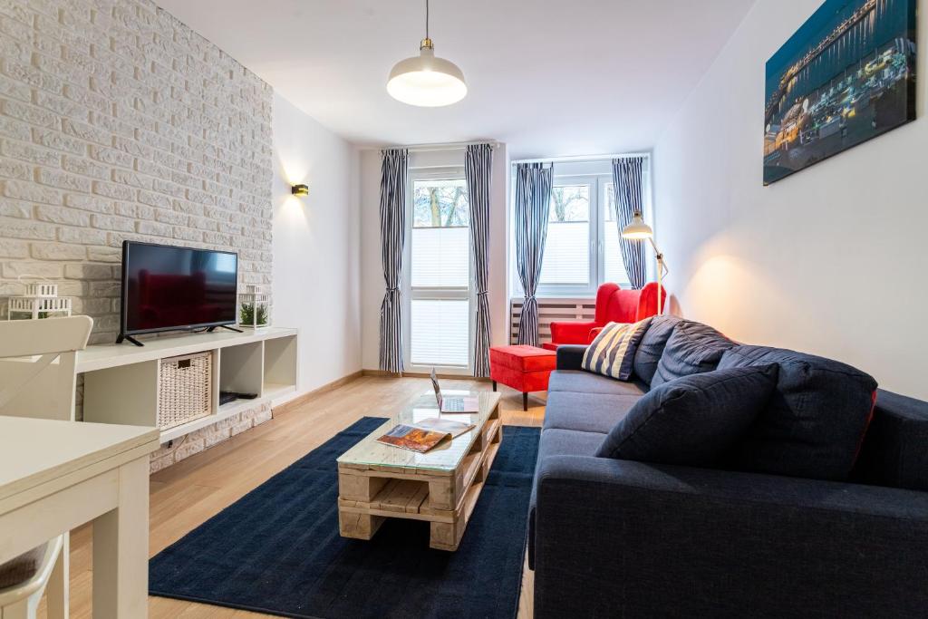 a living room with a blue couch and a tv at Victus Apartamenty, Apartament Livia in Sopot