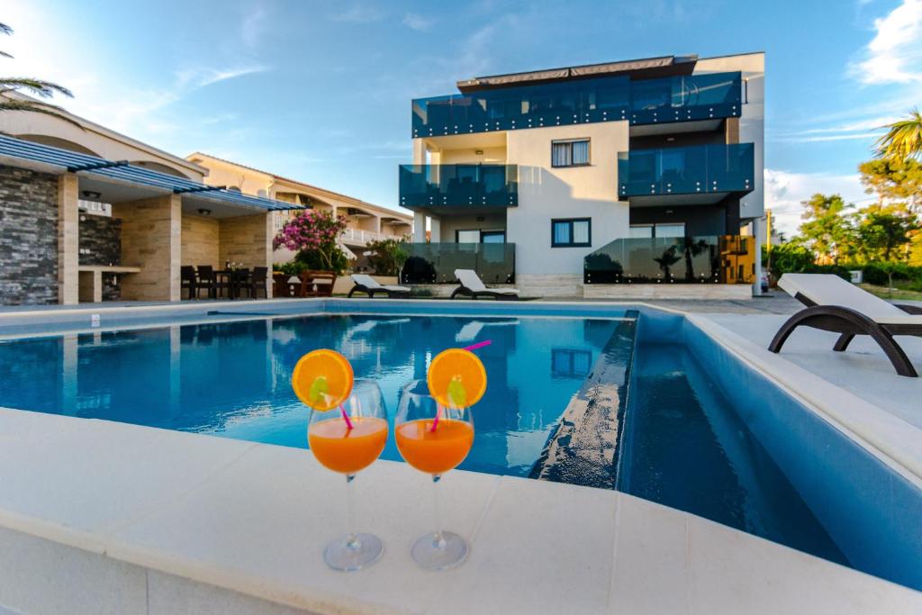 a swimming pool with two glasses of orange cocktails at Resort Mirakul in Vir