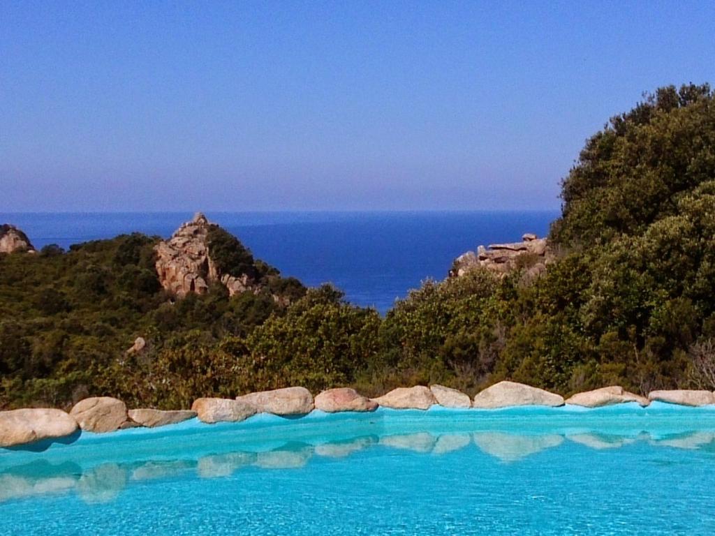 een zwembad met de oceaan op de achtergrond bij Villetta Rocchi - Costa Paradiso in Costa Paradiso