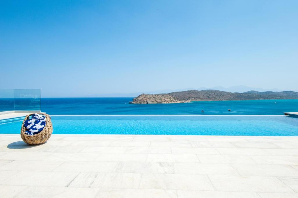 a basket sitting next to a swimming pool with the ocean at Villa Dimitra by Elounda Island View Villas in Elounda