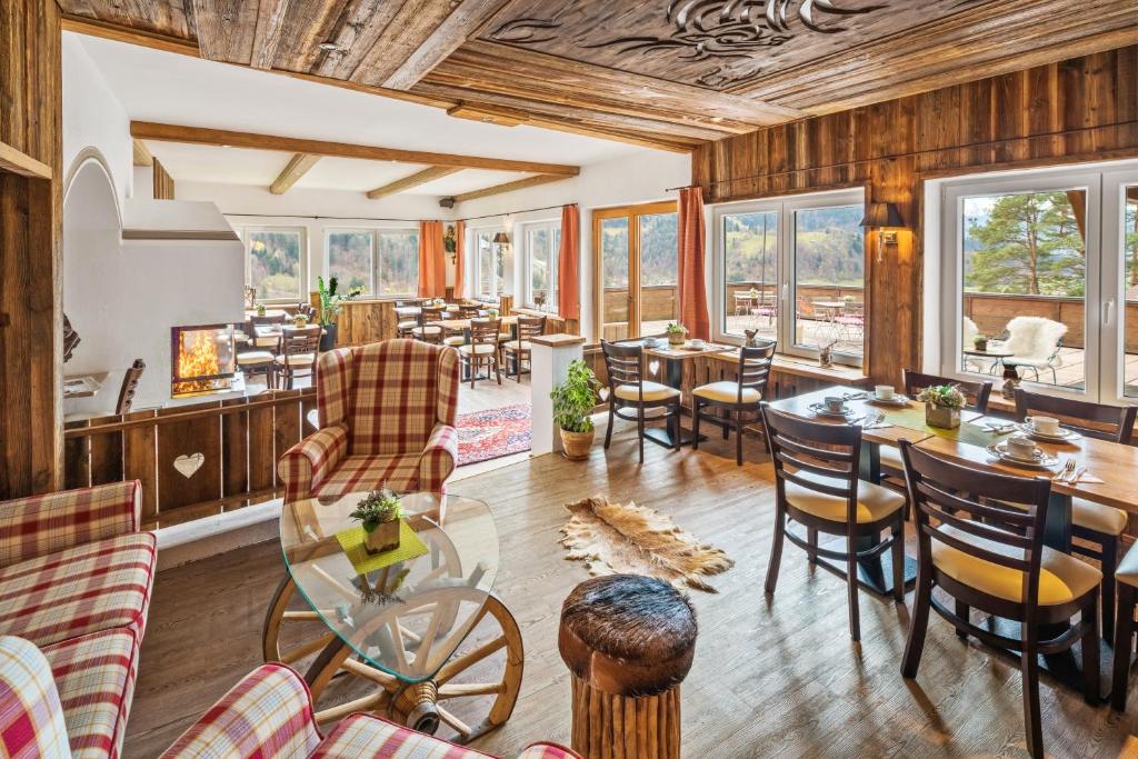 uma sala de jantar com mesas, cadeiras e janelas em Zur Schönen Aussicht Hotel garni em Garmisch-Partenkirchen
