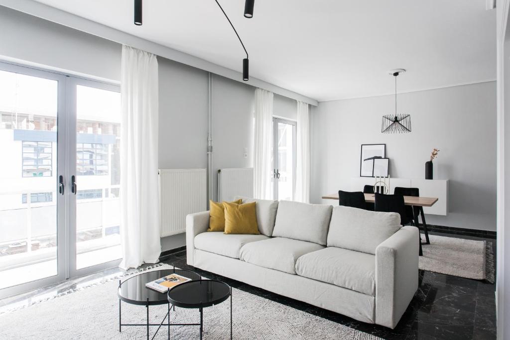 a living room with a white couch and a table at Spacious & Airy 1BR Apartment near HELEXPO Marousi by UPSTREET in Athens