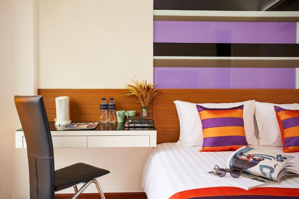 ein Schlafzimmer mit einem Bett mit einem Stuhl und einer farbenfrohen Wand in der Unterkunft Studio Asoke in Bangkok