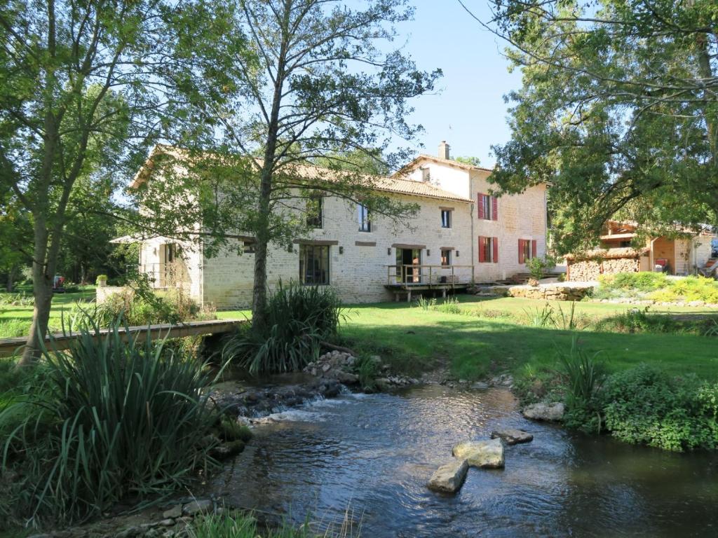 a garden with a stream in front of a house at Le Moulin de Charzay, éco-gîte familial en Deux-Sèvres, Nouvelle Aquitaine 