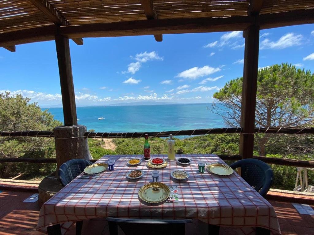Villa San Marco - Casa esclusiva nel Sinis في سان جيوفاني دي سينيس: طاولة طعام وإطلالة على المحيط