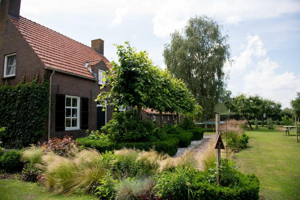 einen Garten vor einem Haus mit Bach in der Unterkunft Gastenverblijf Het Voorhuis in Herpen