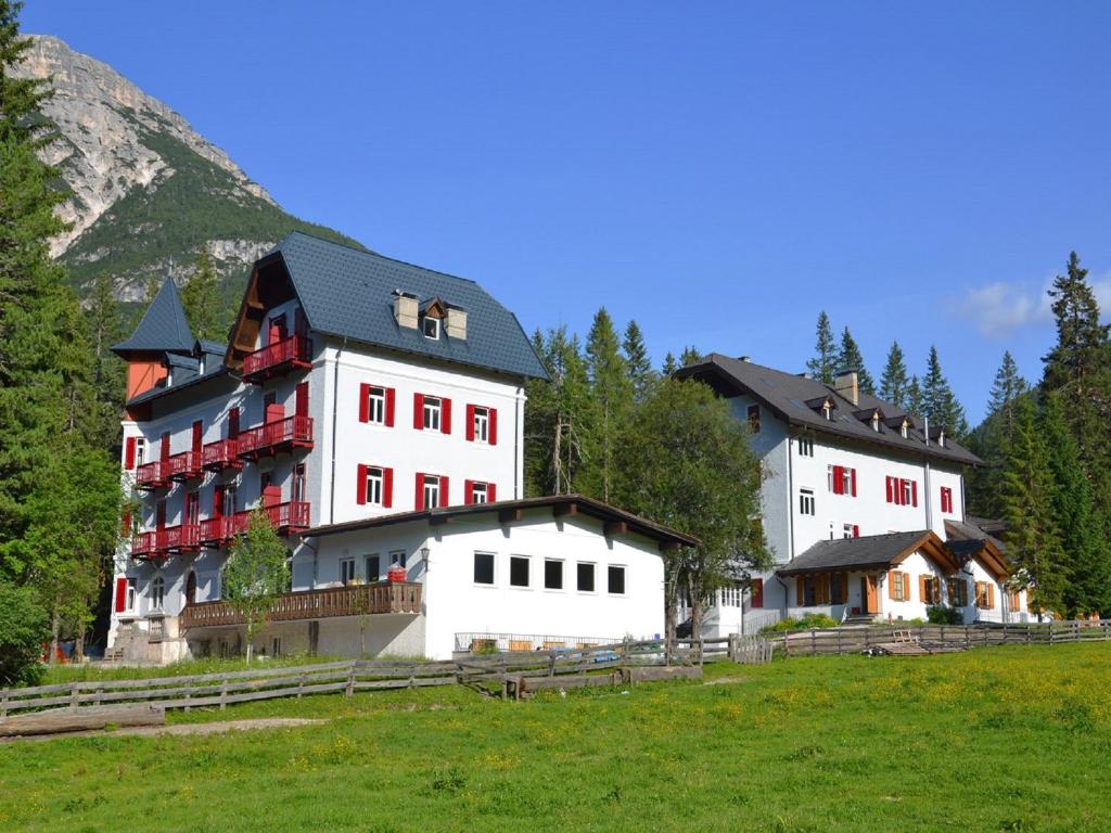 a group of buildings in a field with trees at Hotel Croda Rossa in Carbonin