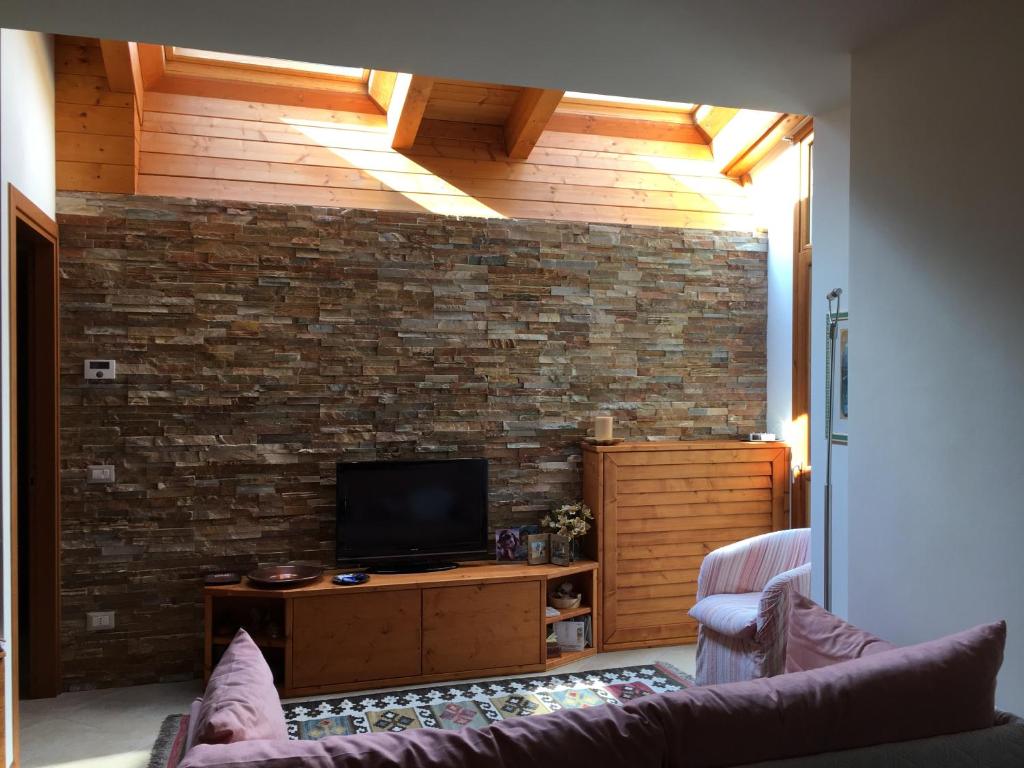 a living room with a tv and a brick wall at La vista sulla Valmalenco in Lanzada