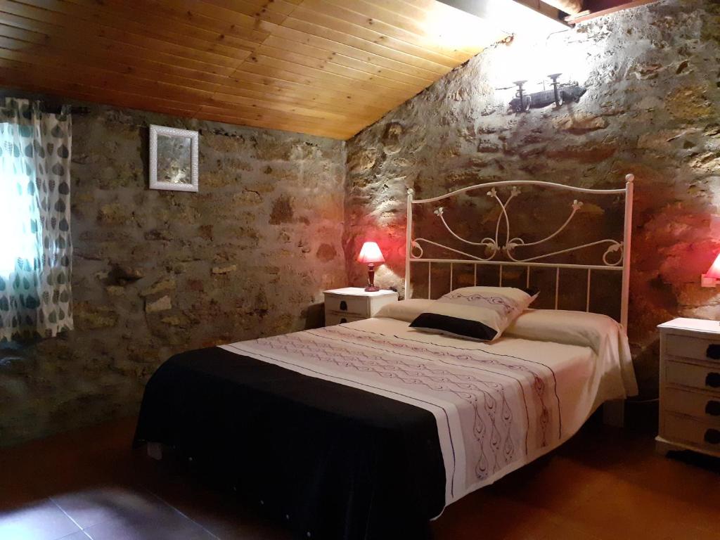 1 dormitorio con cama y pared de piedra en El Patio Chico en Los Loros