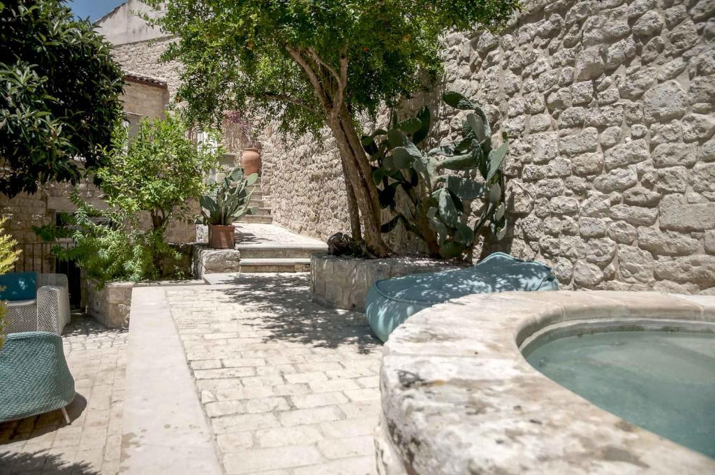 モーディカにあるAnime a Sud - Residenza Hortusの庭にスイミングプールがある石造りの建物