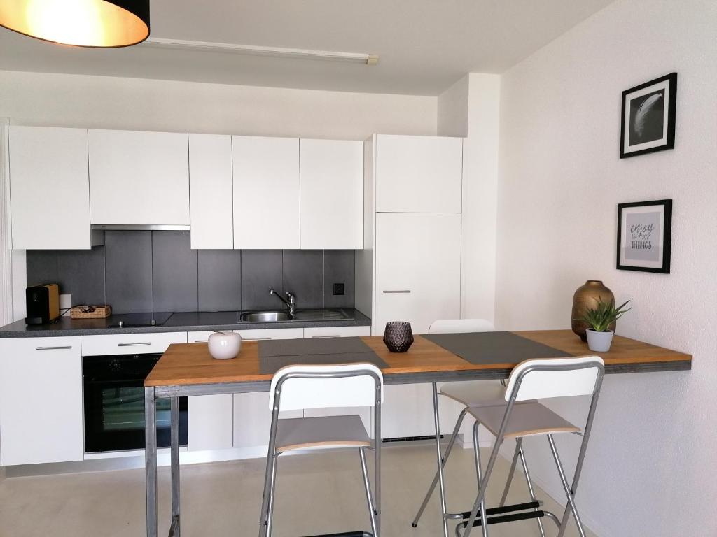cocina con armarios blancos, mesa y sillas en Easy-Living Lucerne City Apartments 1 en Luzern